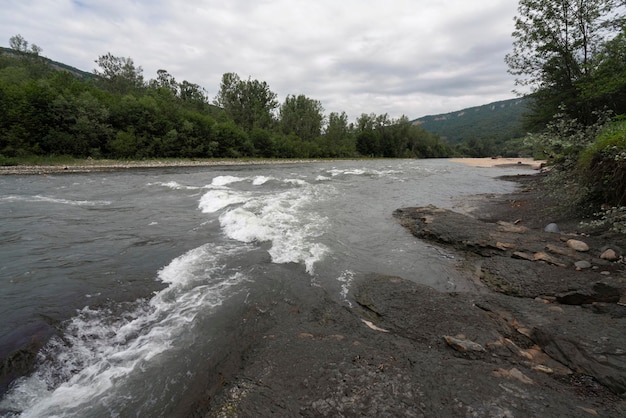 De Belaya-rivier en de Unakoz-kam van het Kaukasusgebergte op de achtergrond op een zonnige zomerdag met wolken Dakhovskaya Republiek Adygea Rusland