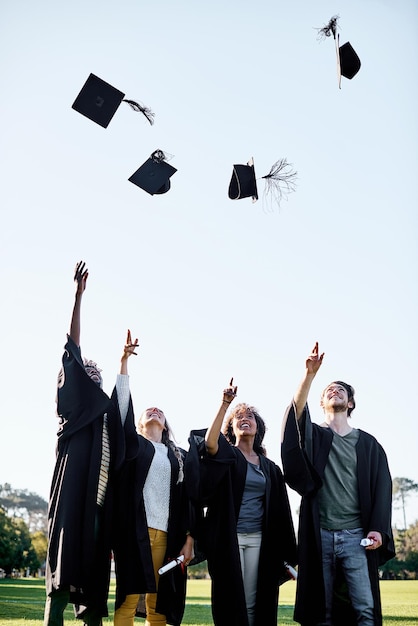 De beloningen zijn allemaal de moeite waard Shot van een groep studenten die hun hoed in de lucht gooien op de afstudeerdag