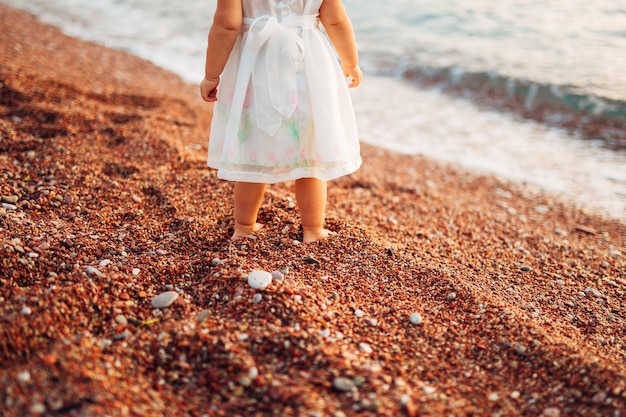 De benen en voeten van kinderen van ouders, het gezin loopt langs het strand