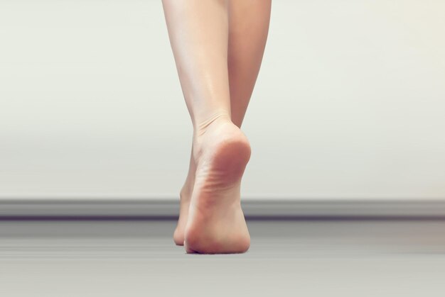 Foto de benen van de vrouw gaan op een grijze vloer