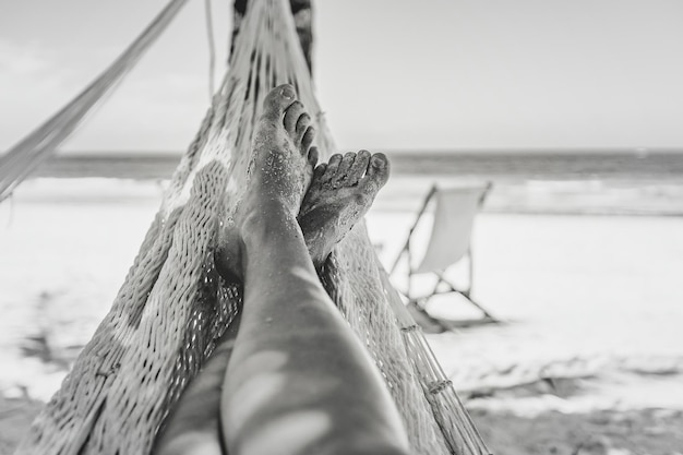 De benen van de vrouw in de hangmat tegen het uitzicht op de oceaan