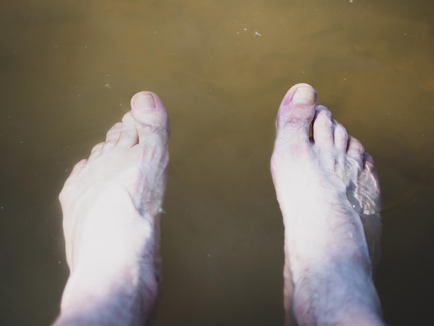 De benen van mannen worden neergelaten in modderige rivierwaterclose-up