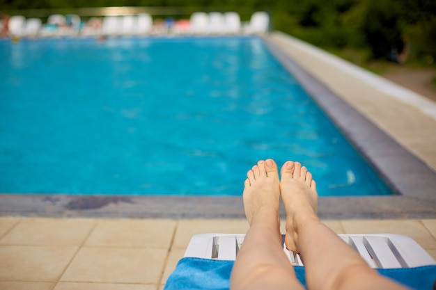 De benen van vrouwen op de achtergrond van het zwembad met blauw water in de open lucht.