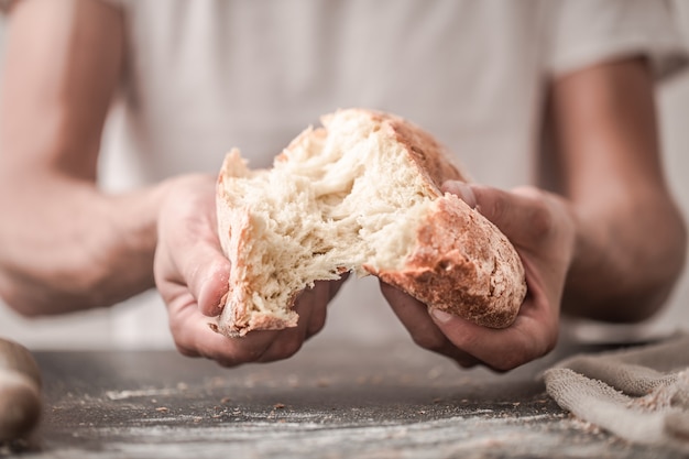 de bereiding van brood, vers brood in handen close-up op oude houten achtergrond, concept voor bakken