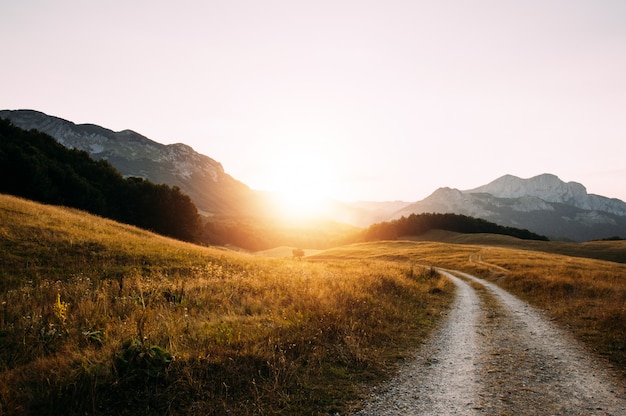 De bergweg van het vuilgrint op zonsondergang