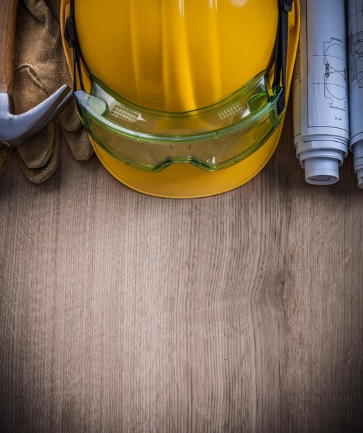 De beschermende blauwdrukken van de hamerbril van handschoenenbril hoed op houten raad