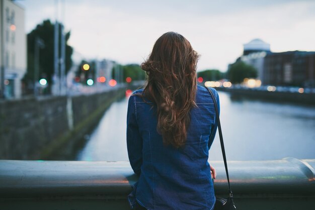 De bezienswaardigheden bekijken Achteraanzicht van een onherkenbare jonge vrouw die het uitzicht over de stad in zich opneemt terwijl ze op een brug staat