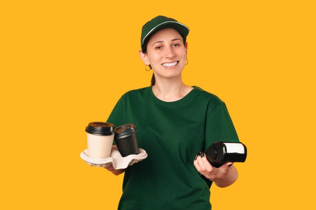 De bezorger in het groen houdt twee kopjes koffie en een betaalautomaat vast