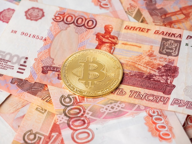 De bitcoin-munt ligt op de achtergrond van Russische roebels. Cryptocurrency-mijnbouw en mijnbouwconcept