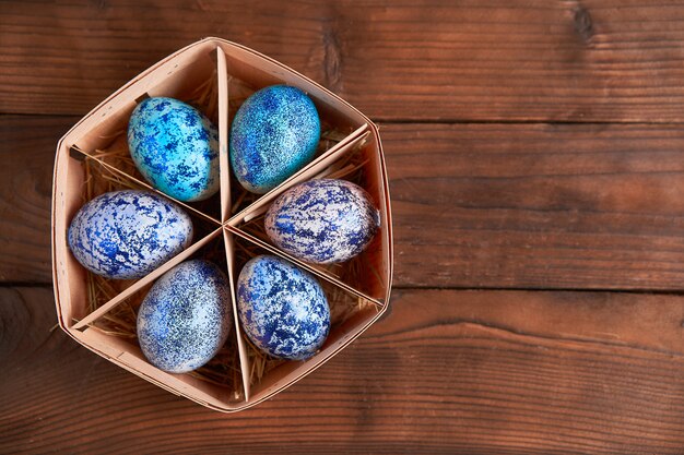 De blauwe eieren van Pasen in mand op houten lijst