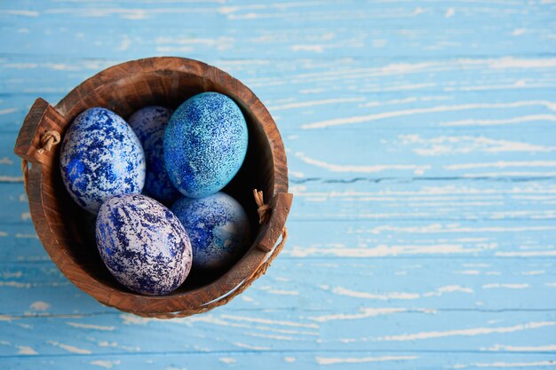 De blauwe eieren van Pasen in mand op houten lijst