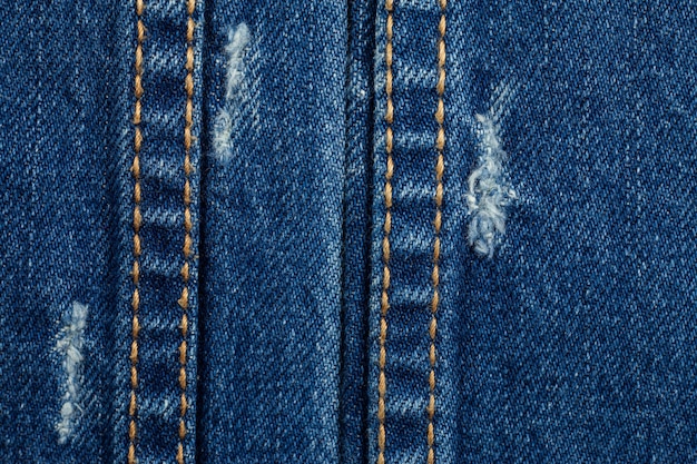 De blauwe gescheurde textuur van denimjeans.