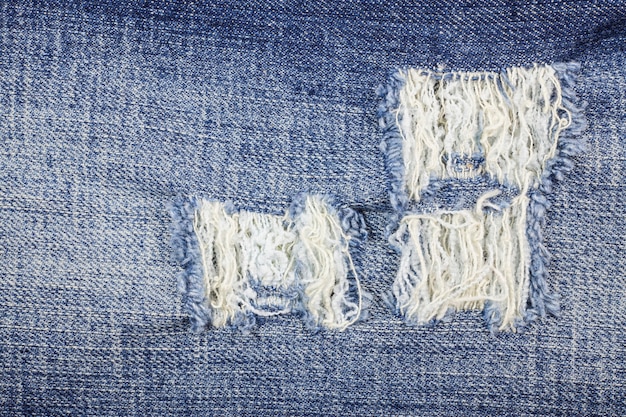 De blauwe gescheurde textuur van denimjeans.