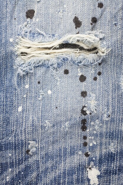 De blauwe gescheurde textuur van denimjeans.