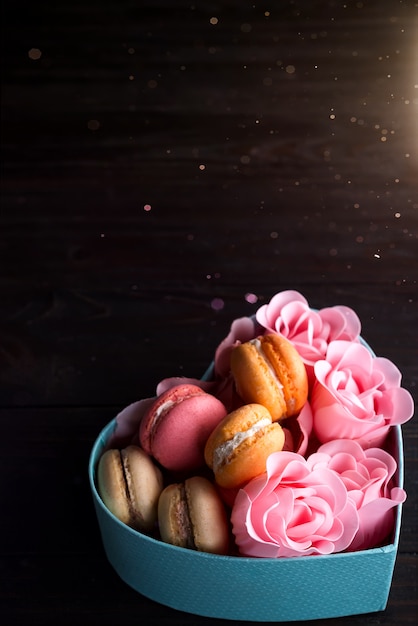 De blauwe hartdoos met makarons en nam op donkere houten achtergrond toe, exemplaarruimte