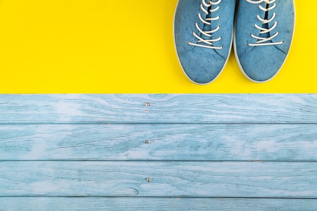 De blauwe schoenen staan op een geïsoleerde gemengde blauwe en gele achtergrond.