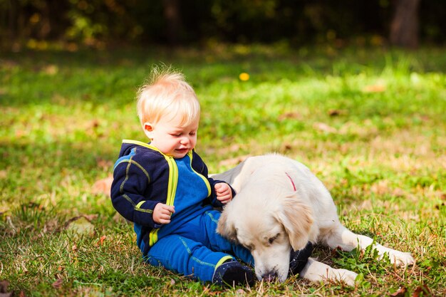 De blije baby op het grasveld met zijn hond