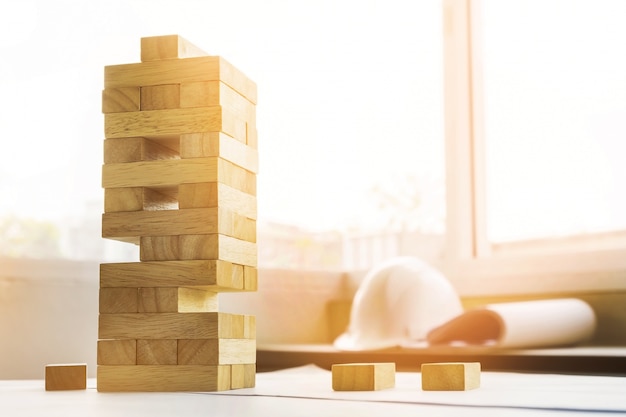 De blokken houten toren spel met architectonische ingenieur plannen of blauwe afdrukken kompassen, potloden en liniaal op houten tafel, plan en gebouw concept