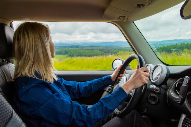 De blondevrouw drijft een auto met bergen