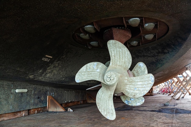 De bodem van een schip ondersteund in een droogdok met azimuth-voortstuwing en dubbele propellers naar achteren