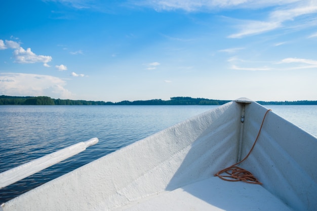 De boeg van een witte roeiboot op een glad blauw meer, kijkend naar de horizon ergens in de diepten van Finland, een goede zomerdag. Vakantie aan het meer.