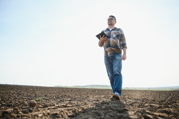 De boer werkt op de grond Mannelijke boer op een geploegd veld en plant granen in de lente in de grond Agrarisch bedrijfsconcept Het verbouwen van voedselgroenten