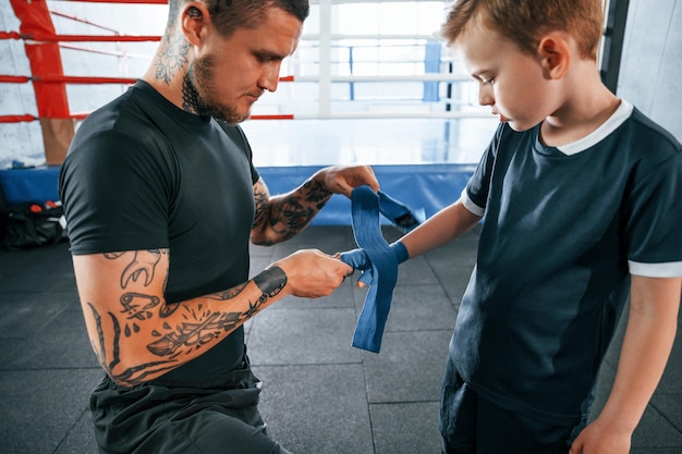 De boksbandage aan Coach is met jongen in de oefenruimte