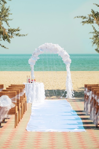 De boog van de huwelijksceremonie met witte bloemen op overzeese achtergrond