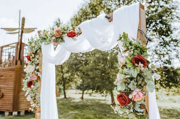 De boog versieren met bloemen en stof voor een huwelijksceremonie in de natuur