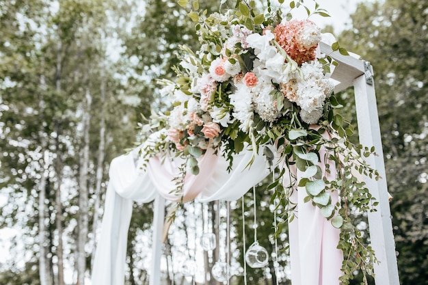 De boog versieren met bloemen en stof voor een huwelijksceremonie in de natuur