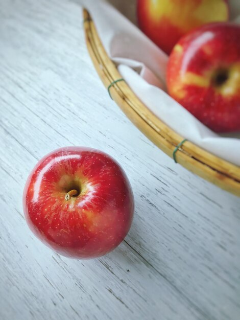 Foto de bovenkant van de rode appel in het mandje op een witte houten tafel