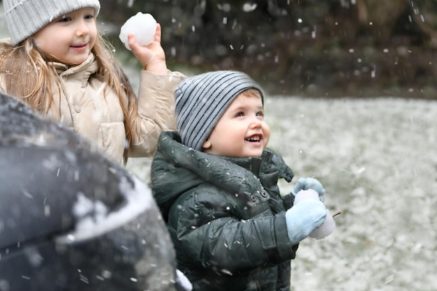 De broer en zus spelen buiten sneeuwballen