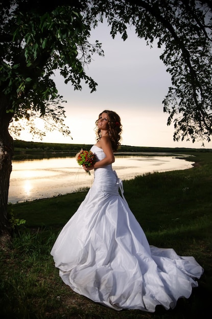 De bruid die de zonsondergang aan de rivier bewondert