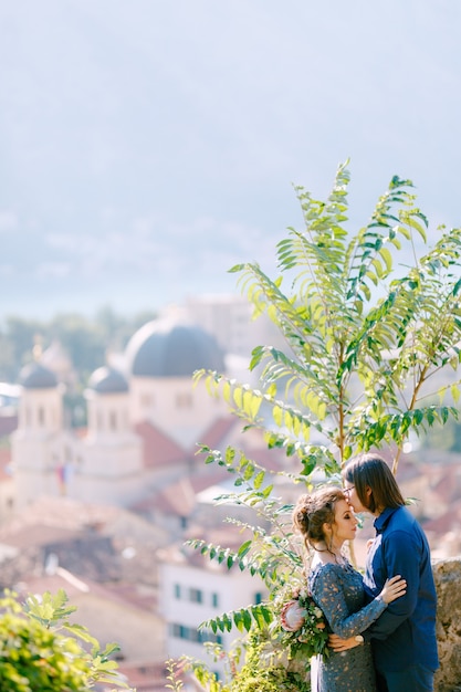 De bruid en bruidegom knuffelen op het observatiedek met een schilderachtig uitzicht op de oude binnenstad van kotor, close-up