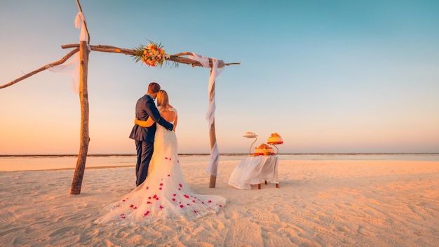 De bruid en bruidegom onder overwelfde galerij op strand. romantische bruiloft achtergrond. bruid en bruidegom romantisch