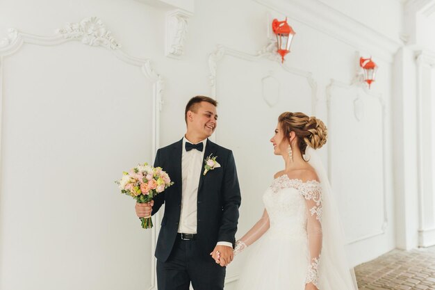 De bruid en bruidegom op een wandeling op de witte muur als achtergrond