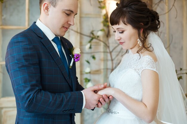 De bruid en de bruidegom in huwelijkskleren omhelzen thuis. Paar verliefd na een huwelijksceremonie