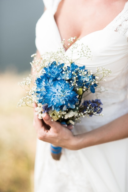 De bruid houdt een bruidsboeket vast met blauwe bloemen