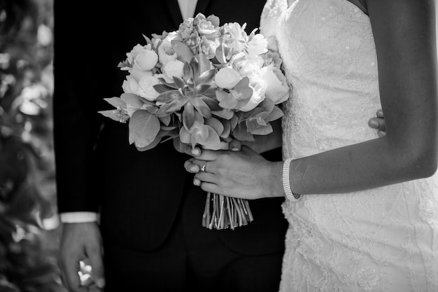 de bruid houdt een bruidsboeket vast tijdens een wandeling. zwart-wit foto