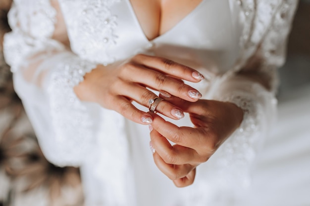De bruid houdt een gouden ring in haar handen close-up ochtend van de bruid trouwdag open schouders sexy meisje