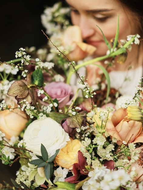 Foto de bruid houdt een huwelijksboeket en snuift bloemenclose-up, groot mooi boeket