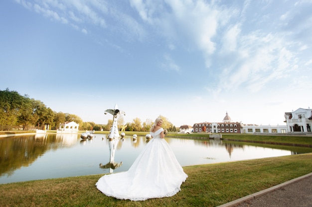 De bruid in een witte jurk staat in de herfst park