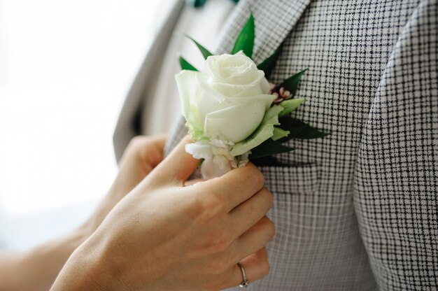 De bruid zet een corsages op het jasje van de bruidegom.