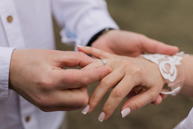 Foto de bruidegom doet een gouden trouwring om de vinger van de bruid