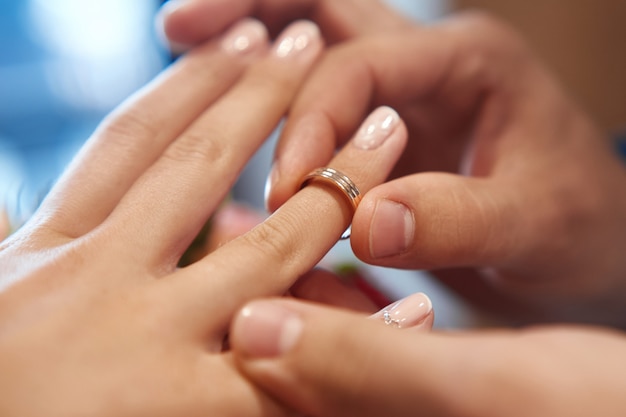 De bruidegom zet de ring op de bruidvinger in huwelijk