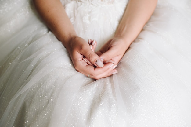 De bruidzitting in haar huwelijkskleding, sluit omhoog van handen