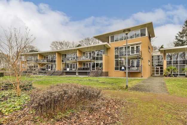 De buitenkant van een geel gebouw met gras en bomen