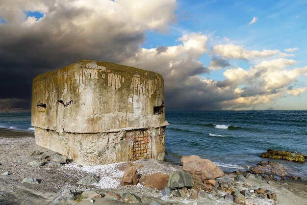 De bunker staat op het strand bij de Zwarte Zee met een oorlog op de achtergrond van een bewolkte hemel