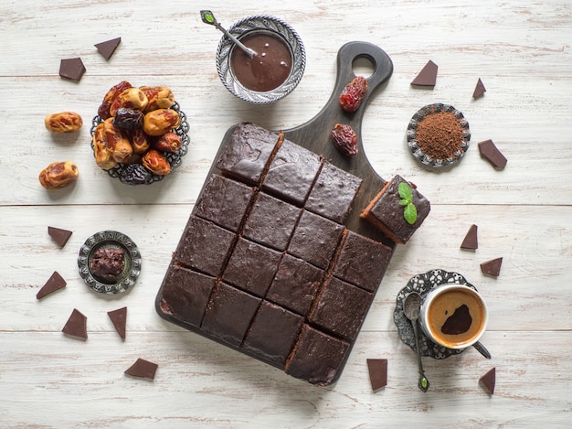 De cake van de chocoladebrownie met data op witte houten lijst