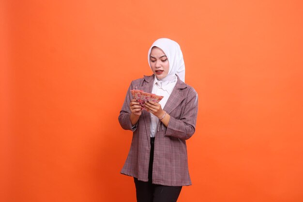 De charme van een mooie Aziatische vrouw met een hijab schokte beide handen die een rupiah-biljet vasthielden en telden.